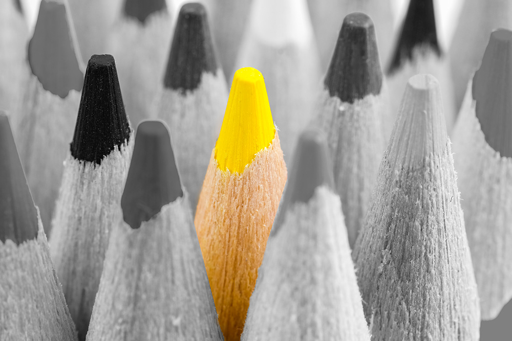 One yellow pencil standing out among gray pencils - representing doing things differently