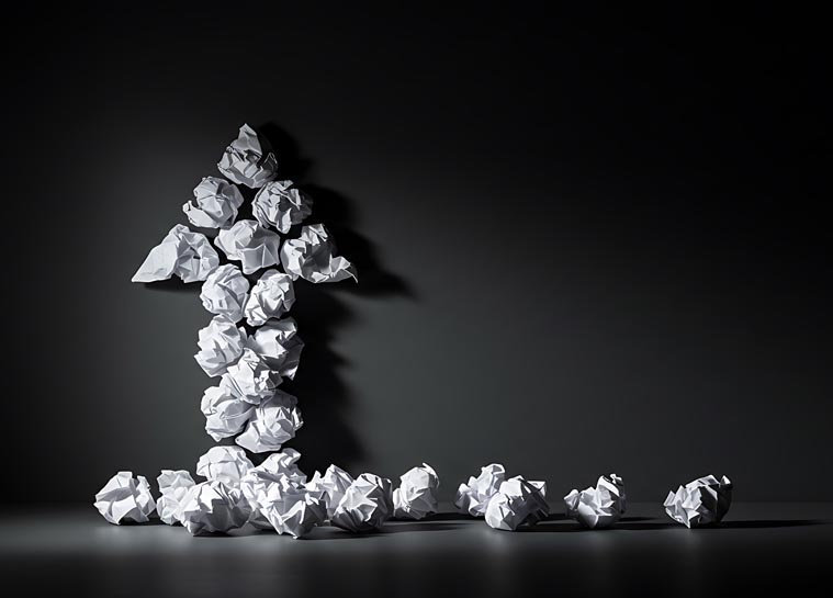 Crumpled paper arrow pointing up, representing iterative content creation and growth